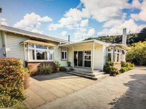 a white house with a porch and a driveway at School Lane Guesthouse in Whangarei