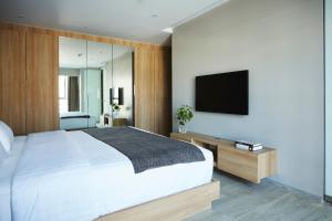 a bedroom with a large white bed and a flat screen tv at Aspira Tropical Residence Thong Lor in Bangkok