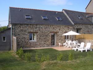 a stone house with white chairs and an umbrella at Le Casino à larmor in Plougastel-Daoulas