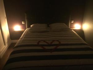 una cama con un corazón pintado en una habitación oscura en L’Edaines, en Bagnoles de l'Orne
