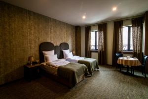 um quarto de hotel com uma cama, uma mesa e janelas em Apricot Hotel Yerevan em Yerevan