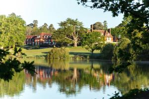 a house is reflected in the water of a lake at Champneys Forest Mere in Liphook