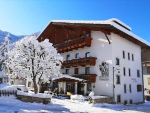 a large white building with a tree in the snow at Hotel Brunella in San Vigilio Di Marebbe