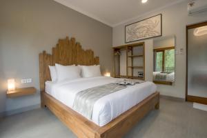 um quarto com uma cama grande e uma cabeceira em madeira em Asanaya Suites em Canggu