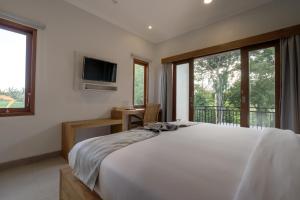 um quarto com uma cama, uma televisão e janelas em Asanaya Suites em Canggu