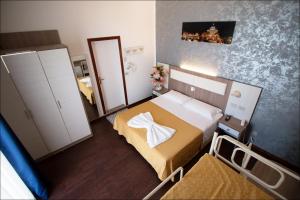 a small bedroom with a bed and a mirror at Hotel Belfiore in Misano Adriatico