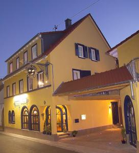 un gran edificio amarillo con un reloj. en Cleo´s Hotel Kallstadt, en Kallstadt