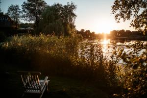 a bench sitting in front of a lake with the sunset at Seehotel Töpferhaus in Alt Duvenstedt