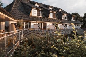 a house with a gambrel roof with a staircase in front of it at Seehotel Töpferhaus in Alt Duvenstedt