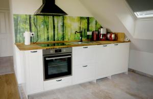 a kitchen with white cabinets and a sink and a painting at Ferienwohnung am Mühlenteich in Beelitz