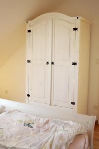 a white cabinet in a bedroom with a bed at Ferienwohnung am Mühlenteich in Beelitz