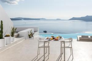 a table on a balcony with a view of the ocean at The Saint Hotel in Oia