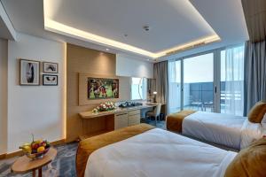 a hotel room with two beds and a desk at The S Hotel Al Barsha in Dubai