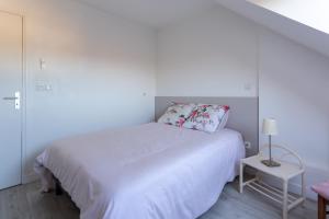 a white bedroom with a white bed and a table at Le Mancini - Parking et Terrasse in Mayenne