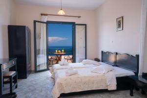 two beds in a bedroom with a view of the ocean at Niforos Panorama in Vovikes