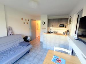 een woonkamer met een bank en een keuken bij 2 pièces Front de Mer ensoleillé et calme accès direct plage in Cabourg