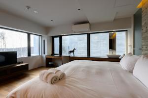 a bedroom with a large white bed with a dog in the window at Sekka Sekka in Niseko