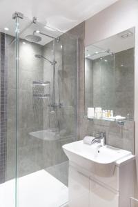 a bathroom with a sink and a glass shower at Citystay - Hinton House in Cambridge