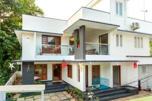 a white house with a front porch and stairs at Poetrie Homestay in Ernakulam