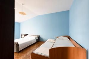 two beds in a room with a blue wall at Apartments Golubić in Sveti Petar