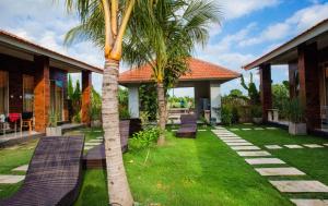 a palm tree in front of a house with benches at Umah Nugraha in Canggu