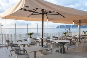 a restaurant with tables and chairs with the ocean in the background at Diana Grand Hotel in Alassio