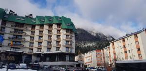 a large building with a green roof in a city at Apartament Silva Busteni in Buşteni