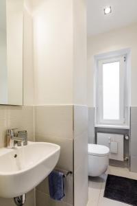uma casa de banho branca com um lavatório e um WC em Lago Welcome Place d'Armes I em Luxemburgo