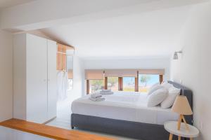 a white bedroom with a large bed and a window at Naftilos Residences II in Potokáki