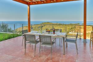una mesa y sillas en un patio con vistas al océano en Aries Villas, en Skiathos