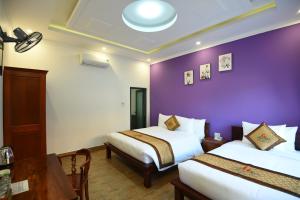ein Hotelzimmer mit 2 Betten und einer lila Wand in der Unterkunft Đồi Sao Phú Quốc in Phu Quoc