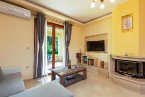 een woonkamer met een open haard en een televisie bij GreenLand Villa in Khoumérion