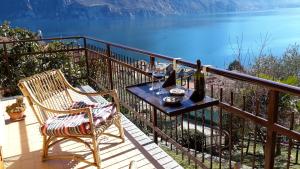 einen Tisch und einen Stuhl auf einem Balkon mit Blick auf das Wasser in der Unterkunft IseoLakeRental - Casa Anita in Riva di Solto