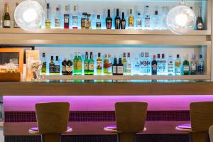 Eine Bar mit drei Stühlen davor und Flaschen Alkohol in der Unterkunft Pines Hotel in Athen
