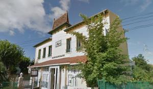 Una vieja casa blanca con un árbol delante de ella. en Auberge des Écluses, en Carrières-sous-Poissy