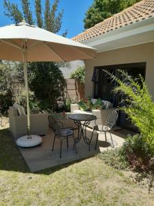 a patio with a table and chairs and an umbrella at Cottage@Somerset in Somerset West