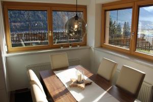a dining room with a table and chairs and windows at Ferienwohnung Auszeit Stubai in Fulpmes