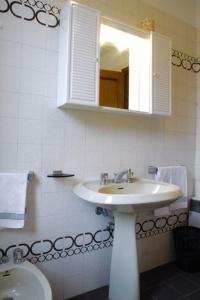 a white bathroom with a sink and a mirror at Centro Residenziale Maestoso in Viareggio