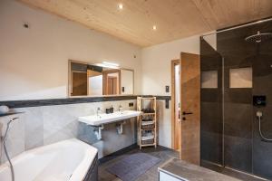 un bagno con vasca, lavandino e doccia di Alpenchalet "DAHOAM" a Going Altre 25 foto