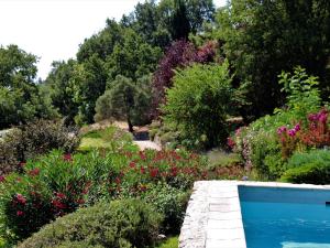una piscina en un jardín con flores y árboles en Apartment La Bachasse by Interhome, en Carros
