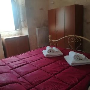 Un dormitorio con una cama roja con toallas. en Trulli Manuela 2, en Locorotondo