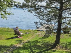 a woman sitting in a chair next to a lake at Holiday Home Tuulikannel by Interhome in Hillilä