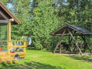 a wooden gazebo with a bench in a yard at Holiday Home Tuulikannel by Interhome in Hillilä