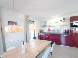 a kitchen with red cabinets and a wooden table at Holiday Home Oesterdam Resort-1 by Interhome in Tholen