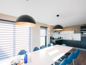 a kitchen with a white table and blue chairs at Holiday Home Oesterdam Resort-1 by Interhome in Tholen +16 photos
