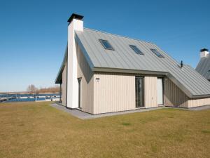 een witte schuur met een grijs dak op een grasveld bij Holiday Home Oesterdam Resort-1 by Interhome in Tholen