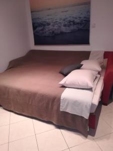 a bed with white pillows and a painting on the wall at Šibenik Gorica Studio apartman 5XL in Šibenik