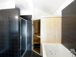 a bathroom with a tub and a shower with blue tiles at Holiday Home Oesterdam Resort-1 by Interhome in Tholen +11 photos