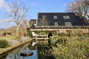 une maison avec un étang en face d'un bâtiment dans l'établissement Gastenverblijf Eenink, à Zelhem