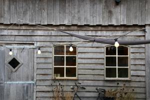 two windows on the side of a wooden building with lights at Gastenverblijf Eenink in Zelhem
